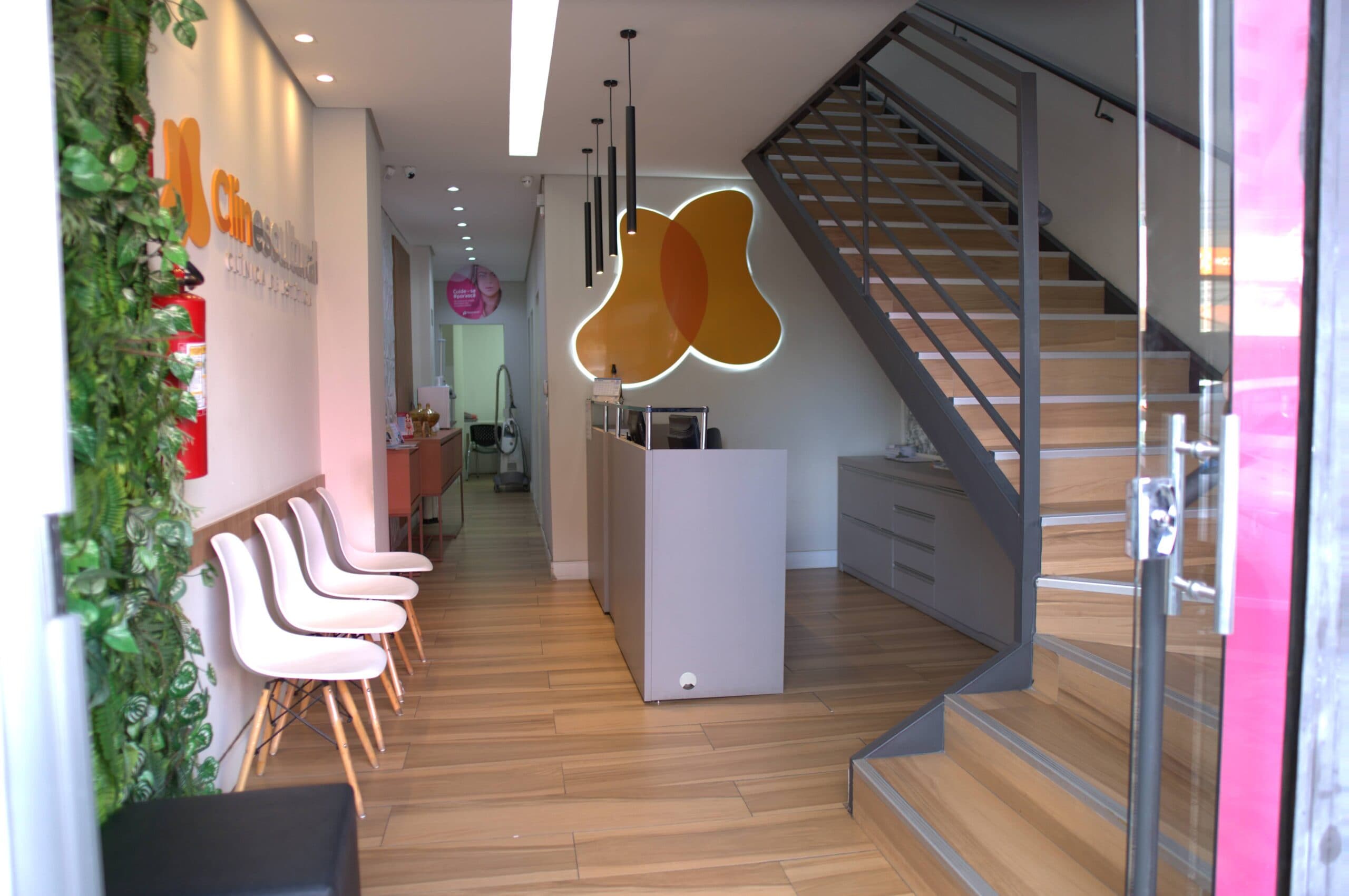 Hall da clínica com escada moderna e logo iluminado
